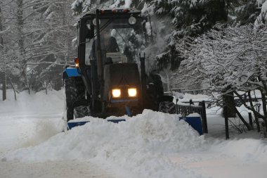 Kar yağışı. Kar temizleme makineleri. Traktör şehrin yollarındaki karları kaldırır. Kış kasırgası. Yüksek kalite fotoğraf