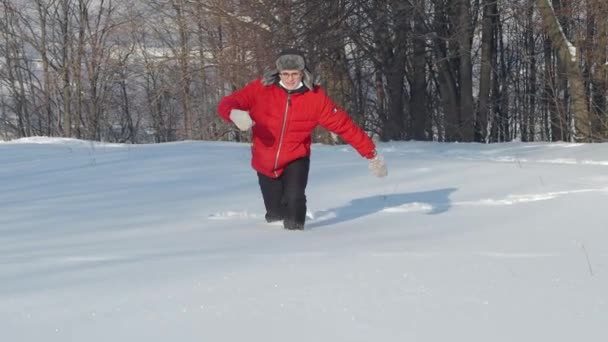 Молодий чоловік проходить крізь глибокі снігопади взимку на полі . — стокове відео
