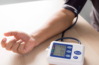 Genç adam kan basıncını el bilgisayarıyla ölçtü ve basıncın normalden daha yüksek olduğunu gördü.