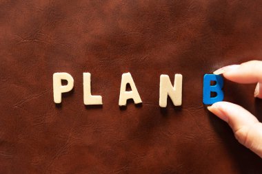 Kadınlar kahverengi arkaplandaki Plan B metnini elle seçerler. strateji kavramları
