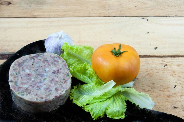 Queijo de porco on the table with garlic, lettuce and tomato around