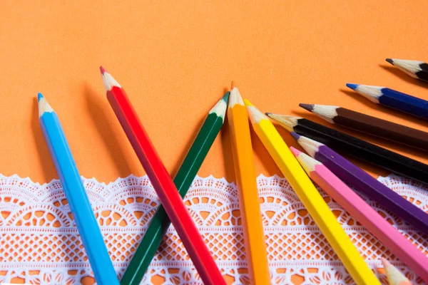 Turuncu arkaplandaki beyaz dantelli renkli kalem.