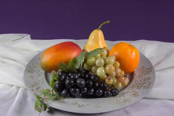 Antique plastic fruits on top of table with background in purple  tone