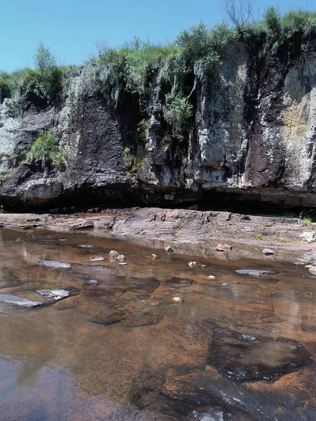 Kayalıklarda mağara, önünde nehir.
