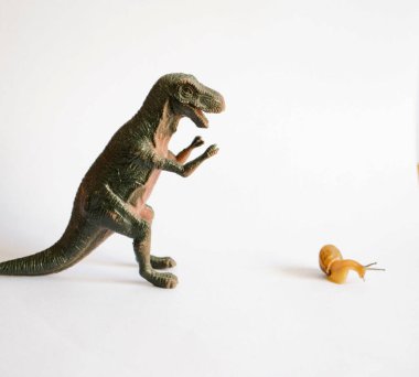 Oyuncak dinozor Whit Whit arka planından kaçan salyangoz.