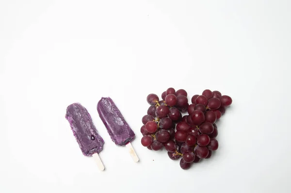 Beyaz arka planda kırmızı dondurma ve üzüm.