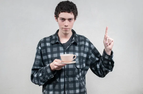 Man in plaid shirt sipping coffee with neutral background