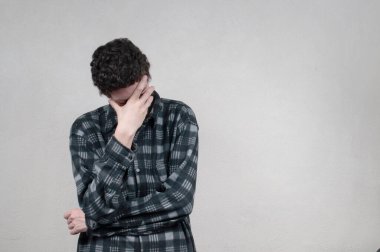 Gri arka planda poz veren genç yakışıklı adam.