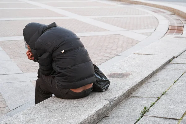 Depresyonda olan evsiz yetişkin adamlar bir şehir caddesinde oturuyor.