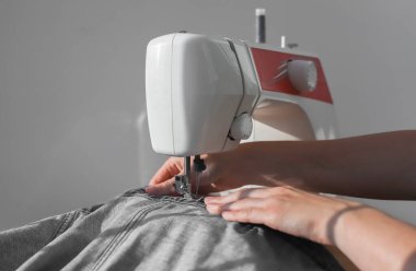 Dikiş makinesinin üzerindeki Denim bezi yakın plan. El işçiliğinde kadın elleri