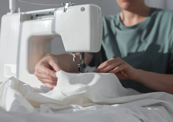 Хлопчатобумажная ткань на швейной машинке с швеей на рабочем процессе, крупным планом — стоковое фото