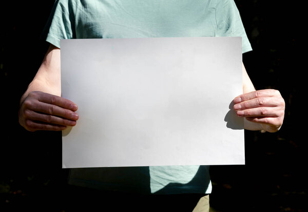 Placard mockup in male hands. Clean white paper with place for text