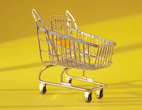 Carrito de compras sobre fondo amarillo con luz natural. Carro de supermercado —  Fotos de Stock