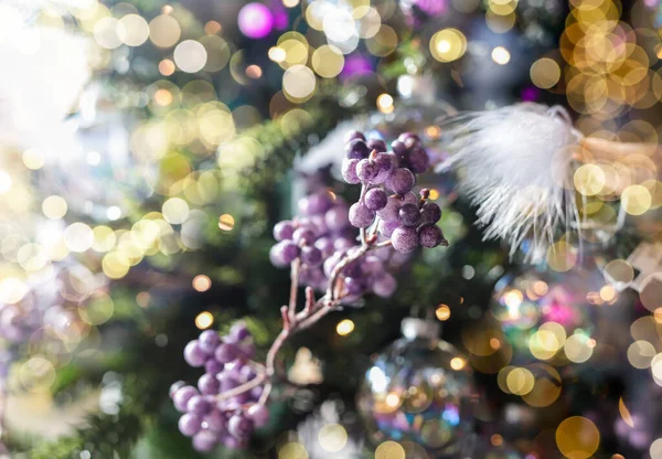 Christmas background with blurred bokeh of Xmas glowing lights and fir tree branch with violet berries — Stock Photo, Image