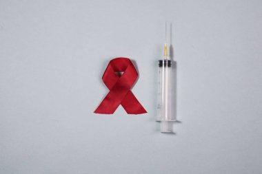Temiz şırınga ve kırmızı kurdele AIDS ve HIV farkındalık gününün sembolü.
