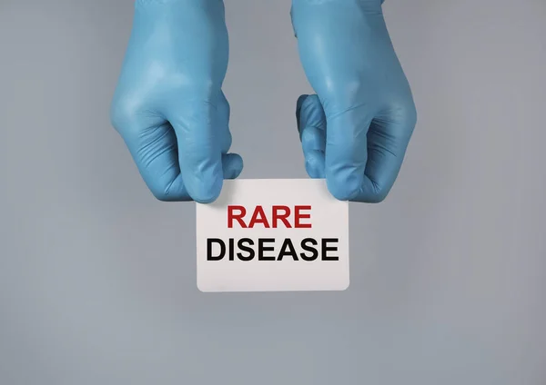 Concepto de enfermedades raras. Palabra sobre papel en las manos —  Fotos de Stock