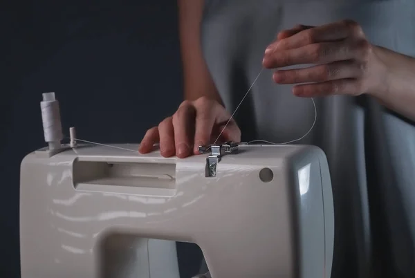 Женские руки кладут нитку на швейную машинку — стоковое фото