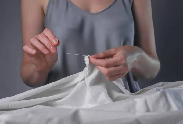 Handen inbrengen draad door naald gat voor het naaien op haar houten bureau — Stockfoto
