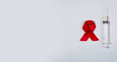 Temiz şırınga ve kırmızı kurdele AIDS ve HIV farkındalık gününün sembolü. Tıbbi Sancak