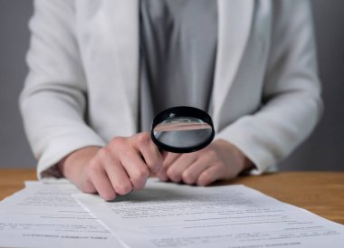 Okumak, iş sözleşmesi üzerinde çalışmak. kağıt yasal anlaşma büyüteç aracılığıyla iş kadını ellerinde yakın çekim