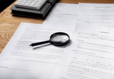 Kağıt sözleşmesi ve ofis masasında büyüteçle birlikte iş belgeleri.