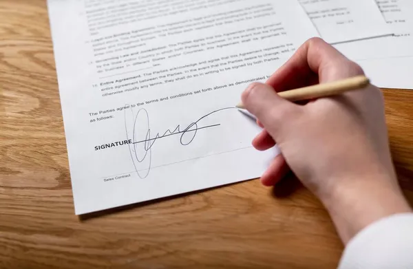 Koncepcja podpisania kontraktu. Kobieta umieszcza swój podpis na prawnej umowie biznesowej z długopisem — Zdjęcie stockowe