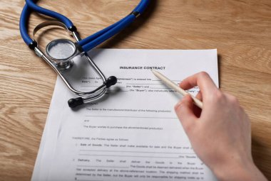 Sağlık sigortası, sözleşme ve steteskop, kalemle.