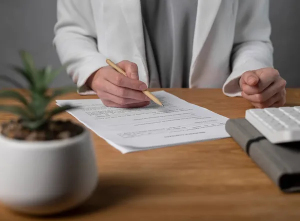 Женщина подписывает юридический бизнес-контракт с ручкой. Подпись женщины за деревянным столом офиса — стоковое фото