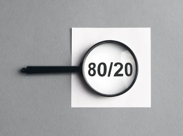 80 20 концепція принципу парето, текст через збільшувальне скло на сірому фоні — стокове фото
