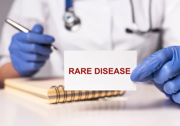 Palabra de enfermedades raras en papel en manos de los médicos —  Fotos de Stock