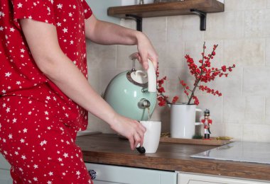 Kadın elleri kışın mutfak masasında çay dolduruyor.