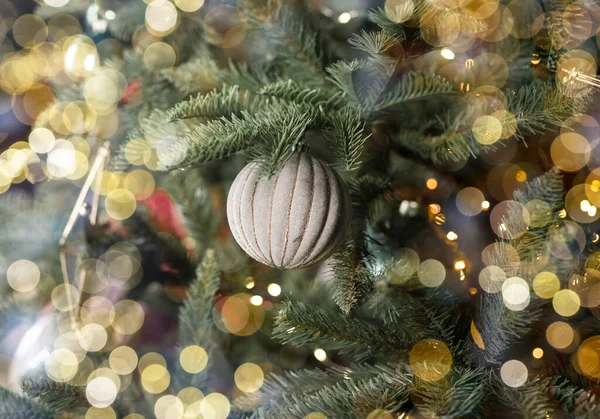 Christmas background with blurred Xmas lights and holiday decor, fir tree bauble on branches, closeup — Stock Photo, Image