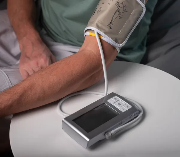 Medição e verificação da pressão arterial. Mão masculina na mesa com ferramenta moderna conectada para check-up cardio em casa — Fotografia de Stock