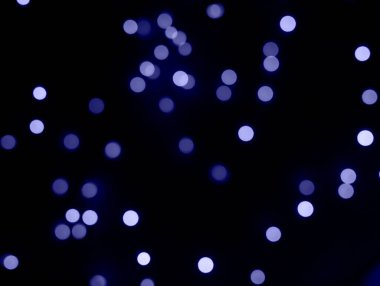 Siyah arka planda Noel çelenginin menekşe ışıkları.