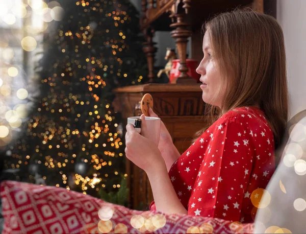 Mujer con taza de té en las manos, sentado en silla en casa acogedora con abeto en las vacaciones de Navidad —  Fotos de Stock