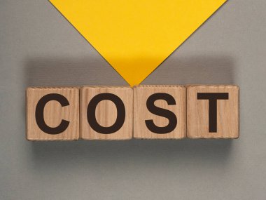 Kelimeye mal oldu. Gri arkaplandaki tahta küplere harfler