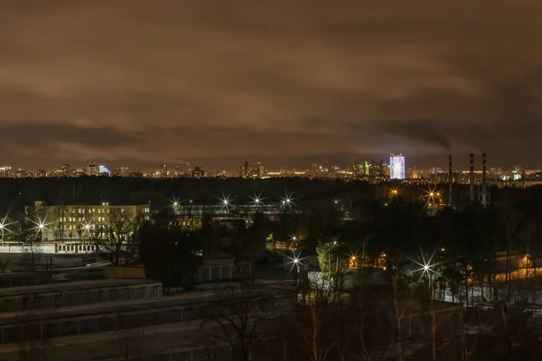 Vista nocturna de la ciudad. Paisaje urbano en crepúsculo con edificios, luces desde la distancia — Foto de Stock