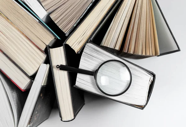 A lencse nagyítása különböző könyvekre. A tudásra és a tanulásra való összpontosítás fogalma — Stock Fotó
