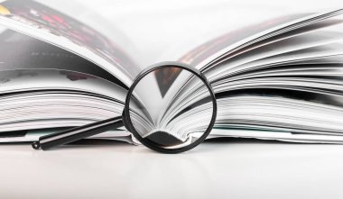 Sayfalarca açık kağıt üzerinde büyüteç. Akademik araştırma kavramı