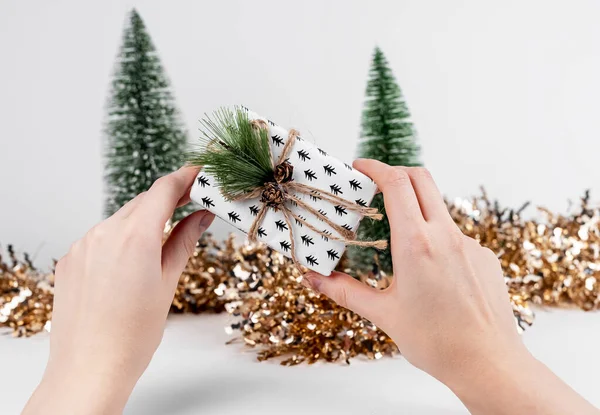 Caja de regalo en las manos y decoración de Navidad con purpurina y abetos —  Fotos de Stock