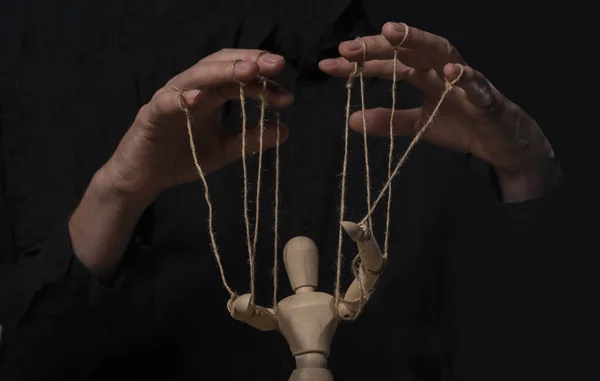 Hands manipulating wood puppet. Master of marionette