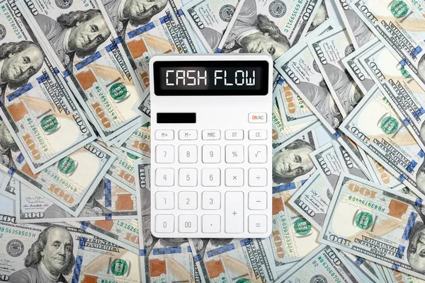 Concepto de flujo de efectivo. Palabra de flujo de caja en calculadora y montón de dólares —  Fotos de Stock
