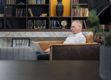 Ciddi, olgun bir iş adamı, gözlüklü, dizüstü bilgisayarlı, internette gezinen, çalışan ya da uzaktan eğitim gören biri. Çevrimiçi iş ve eğitim kavramı