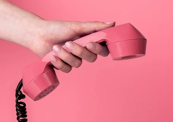 Weibliche Hand mit Vintage-Schnurtelefon auf rosa Hintergrund. Retro-Konzept — Stockfoto
