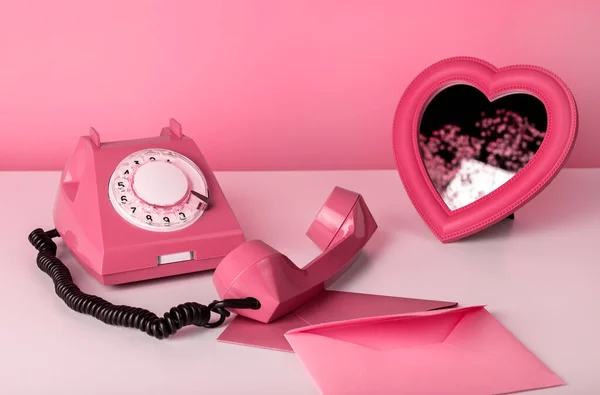 Retro telefon se zrcadlem a obálkami u stolu. Zátiší v růžové barvě. Valentines day concept — Stock fotografie