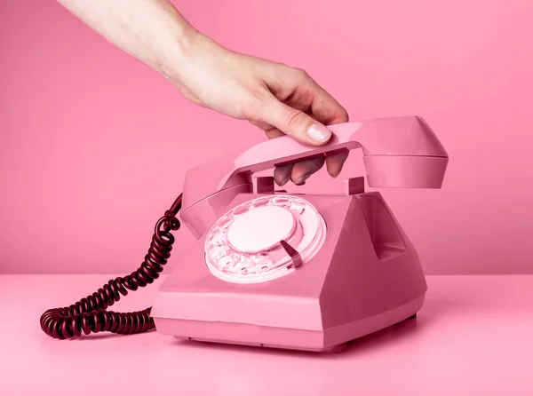 Frau hält Retro-Telefonhörer auf rosa Hintergrund und nimmt Anruf entgegen oder legt auf. — Stockfoto