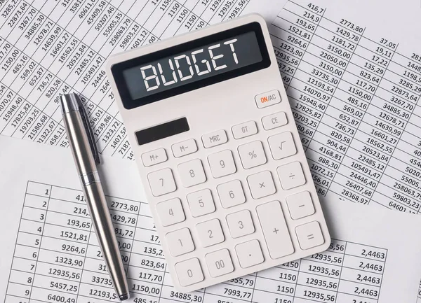 Begrotingswoord over rekenmachine met papieren documenten — Stockfoto