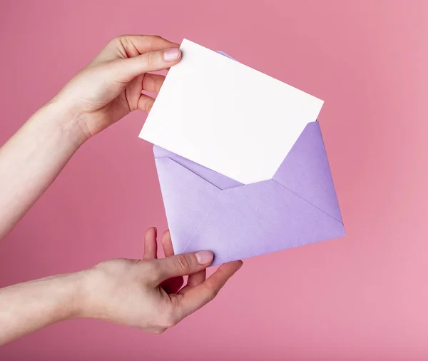 Hands holding blank greeting card in envelope. Valentines day concept. Love letter or holiday invitation mockup. Woman putting card in envelope — Stock Photo, Image