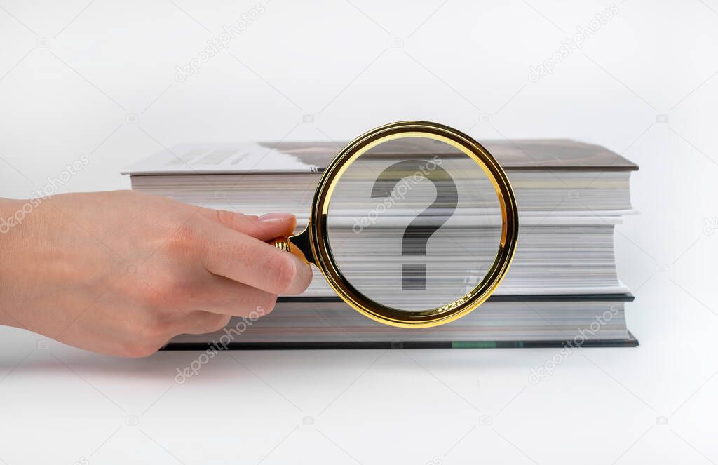 Questions and answers concept. Hand holding magnifying glass near books stack. Important information search. 