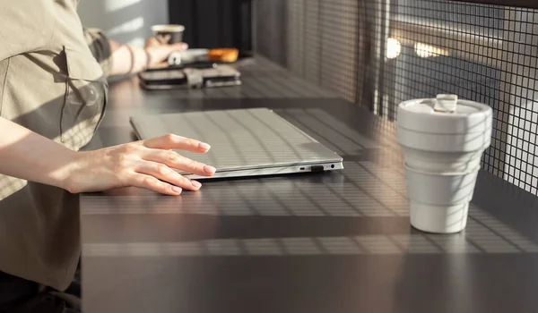 Mulher sentada na mesa do café com laptop fechado e eco cup. Uma mulher a tirar notas. Início do trabalho ou do estudo Fotos De Bancos De Imagens Sem Royalties